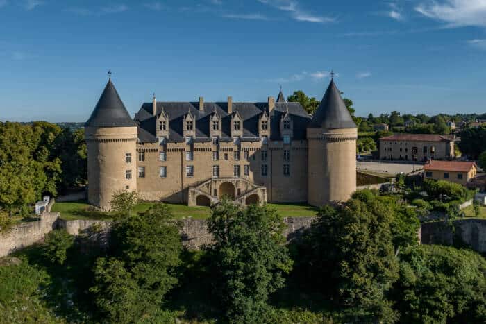 Un château, mélangeant style gothique et renaissance, sur un promontoire, au-dessus d'un parc arboré