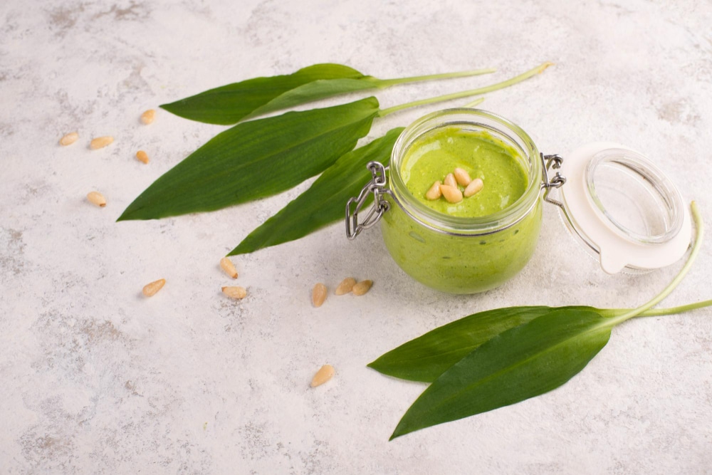 pesto-base-pignons-pin-ail-sauvage-fromage-feta-dans-verre-feuilles-fraiches-texte-blanc